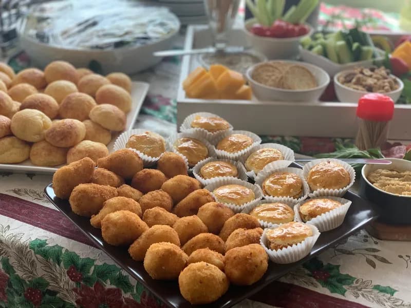 A Christmas table with a platter of pão de queijo, bolinhas de queijo and glazed empadinhas